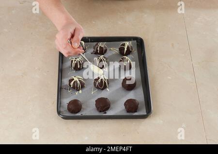 Schokoladen-Toffee-Bälle, weißer Schokolade über Schokoladen-Kuchenbällchen Stockfoto