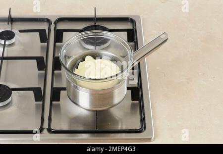 Weiße Schokolade in der Schüssel über dem Topf mit kochendem Wasser schmelzen lassen Stockfoto