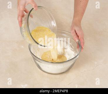 Zitronen- und Blaubeer-Muffins herstellen, Eiermischung gut in Mehl gießen Stockfoto