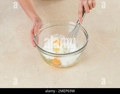 Zucker, Maismehl, Eier und Vanilleextrakt in der Schüssel schlagen, um Creme geduldig für Torte zu machen Stockfoto