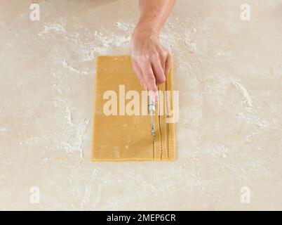 Herstellung von traditioneller österreichischer Torte, Linzertorte, unter Verwendung von geriffeltem Rad, um Teig in Streifen zu schneiden Stockfoto