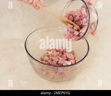 Hähnchen und Schinken-Backkuchen, Füllung, Schinken zu Hackfleischmischung hinzufügen Stockfoto