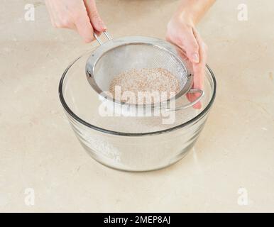 Soda-Brot herstellen, Bicarbonat aus Soda und Vollkornmehl in Schüssel sieben Stockfoto