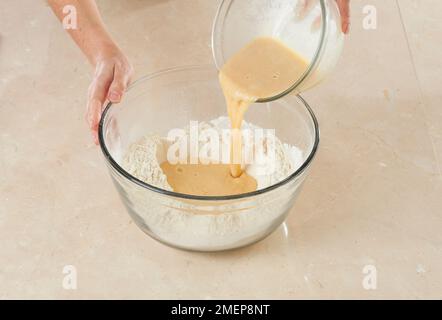 Herstellung von Brioche des rois, Herstellung eines Brunnens in Mehl und Eingießen in die Mischung aus Eiern und Hefe Stockfoto