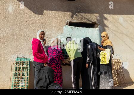ASSUAN, ÄGYPTEN - 29. Dez. 2022. Die Einheimischen kaufen Pita-Brot in einem alten Laden in einem nubischen Dorf in Ägypten Stockfoto