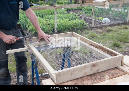 Mann, der ein Trockengestell aus Holz und Draht baut Stockfoto