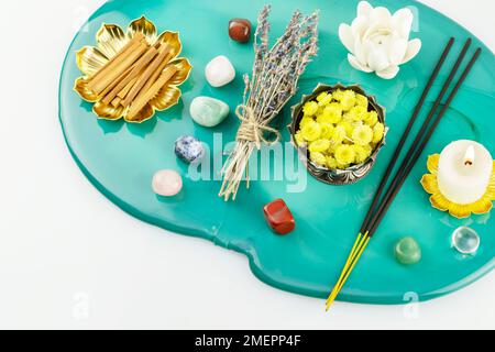 Selbstpflege, heilende Komposition mit Kerzen, Aromastifte, Chakrasteine, Sandelholzstangen und trockenen Blumen auf grünem Marmorpodium. Konzept der Entspannung Stockfoto