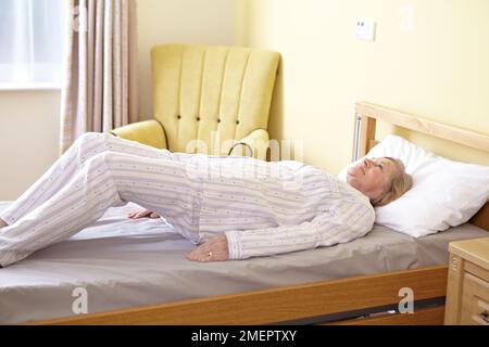 Bewegungsfreiheit im Bett, Brücken, Person liegt auf dem Rücken, Hände zur Seite, Beine nach oben, Knie gebeugt, um Becken oder Boden vom Bett zu heben Stockfoto
