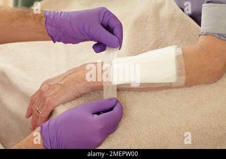 Wundversorgung, Auftragen eines dicken saugfähigen Verbandes auf einen Spezialverband Stockfoto