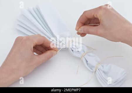 Vorbereitung des Materials für das Krawatten mit Streifeneffekt, bindet das Plisseedetail-Gewebe eng mit einer Schnur, Nahaufnahme Stockfoto