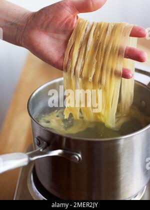 Das Abtropfen von hausgemachten Tagliatelle-Nudeln in die Pfanne Stockfoto