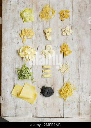 Verschiedene Arten von Pasta auf Holzhintergrund, einschließlich gefüllte Pasta, Pasta mit Farbband, Nudelröhrchen Stockfoto