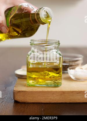 Gießen Olivenöl in kleinen Glas mit weißer Weinessig (vinaigrette) Stockfoto