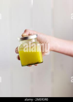 Handgehaltene Glasdose mit hausgemachter Vinaigrette Stockfoto