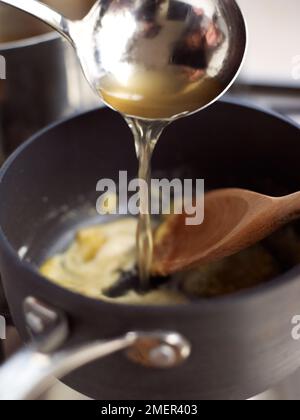 Brühe eingießen und mit Roux (Kochen von Sauce Veloute) mischen Stockfoto