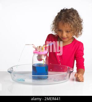 Ein Mädchen, das ein Wasserverdrängungsexperiment macht, 4 Jahre alt Stockfoto