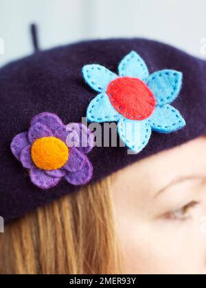 Junge Frau mit Hut und farbenfrohen Emblemen aus Filz Stockfoto