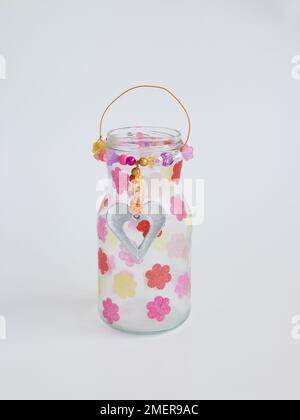 Gläser aus Kerzenglas mit Papiertaschenblumen, silberner Pendelleuchte und Perlen Stockfoto