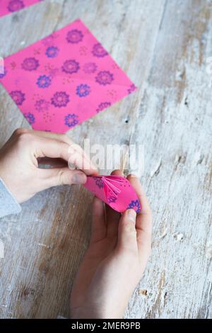 Papierblumen machen, farbenfrohes gemustertes Papier falten Stockfoto