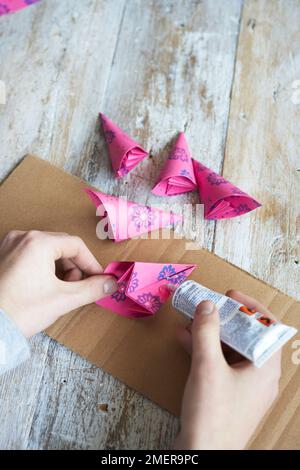 Herstellung von Papierblumen, Falten von bunten gemustertem Papier und Verkleben an Ort und Stelle Stockfoto