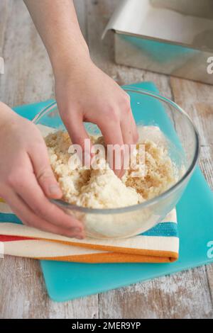 Kokosnussbisse herstellen, getrocknete Kokosnüsse, Puderzucker und Kondensmilch mischen Stockfoto