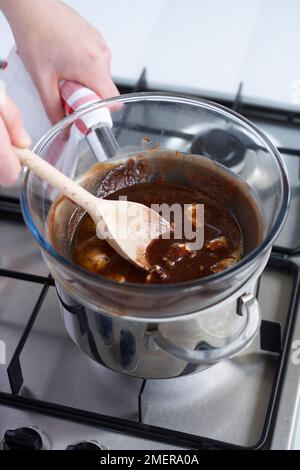 Butter und Schokolade schmelzen in einer Schüssel über einem Kochtopf mit köstlichem Wasser und machen Brownies Stockfoto