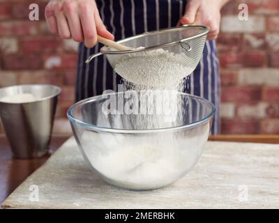 Brot zubereiten, Mehl in eine große Schüssel sieben Stockfoto