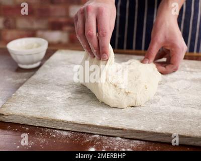 Brot zubereiten, Teig auf Mehlfläche kneten Stockfoto