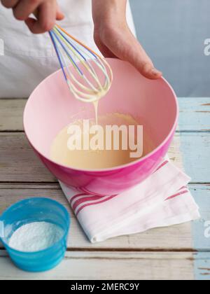 Schneebesen und Puderzucker, um gefrorenen Joghurt herzustellen Stockfoto