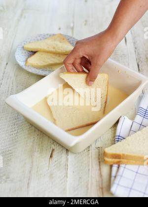 Eierbrot machen, Dreiecke in Milch-Ei-Mischung einweichen Stockfoto