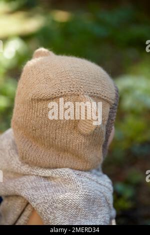 Ein kleiner Junge mit Bärenklava, Balaklava mit Ohren, Rückansicht, 17 Monate Stockfoto