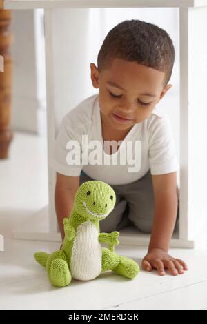 Ein Junge, der mit gestricktem Dinosaurierspielzeug spielt, 3 Jahre Stockfoto