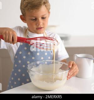Junge rühren Pfannkuchenteig in eine Schüssel, 6 Jahre Stockfoto