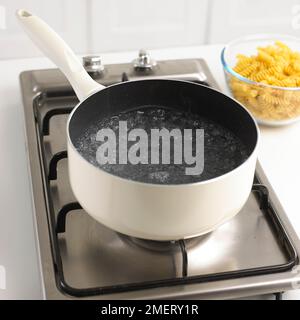 Kochtopf mit kochendem Wasser und Schüssel mit getrockneter Pasta Stockfoto