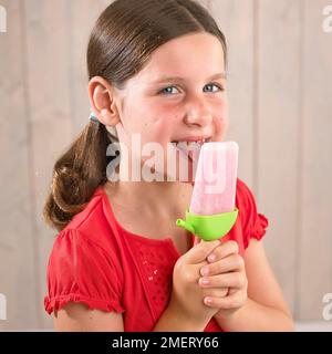 Ein Mädchen leckt einen gefrorenen Smoothy Lolly, 7 Jahre Stockfoto