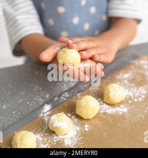 Ein Junge, der weiße Schokoladentrüffel rollt, 4 Jahre Stockfoto