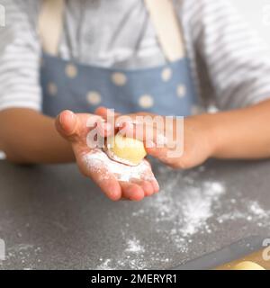 Ein Junge, der weiße Schokoladentrüffel rollt, 4 Jahre Stockfoto