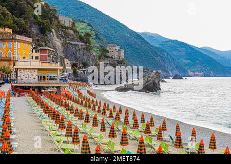 Sonnenliegen und Sonnenschirme, Felsen am Strand di Fegina, hinter dem Torre Aurora Mare, Monterosso al Mare, Cinque Terre, Ligurische Küste, Ligurien Stockfoto