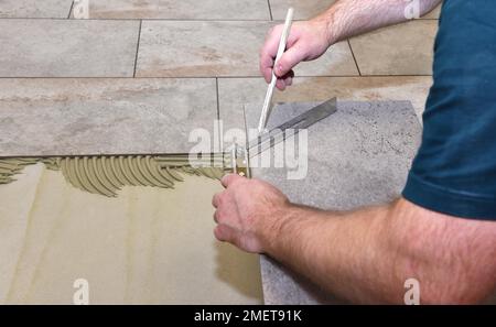 Tiler hat Fliesenkleber aufgetragen und klebt auf neuen Fliesen, Hessen, Deutschland Stockfoto