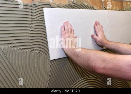 Tiler hat Fliesenkleber aufgetragen und klebt auf neuen Fliesen, Hessen, Deutschland Stockfoto