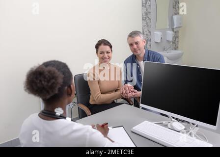 Ein glückliches Ehepaar, bei einem Termin mit einem Gynäkologen oder einem Schwangerschaftsspezialisten. Ein junges Weißes Mädchen mit ihrem Mann bei einer Sprechstunde Stockfoto