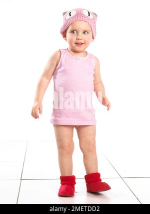 Mädchen mit roten Socken, rosa Oberteil und rosa Wollmütze, 19 Monate Stockfoto