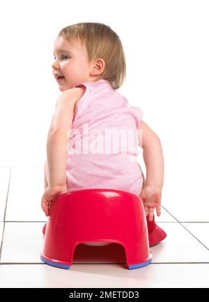 Mädchen sitzt auf einem roten Töpfchen, Rückblick, 19 Monate Stockfoto