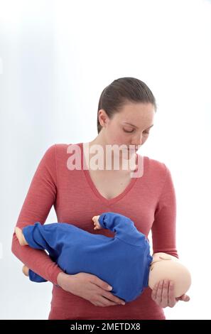 Erste-Hilfe-ärztliche Untersuchungen und Behandlung des bewusstlosen Säuglings mit Hilfe einer Prüfpuppe, die sich in der Aufwachposition befindet Stockfoto