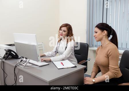 Die Ärztin zeigt dem Patienten den Computerbildschirm, erklärt das elektronische Rezept, ein gutes Ergebnis der medizinischen Untersuchung, gibt Ratschläge.A Youn Stockfoto