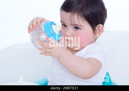 Kleines Mädchen (40 Wochen), das mit einem Plastikbecher spielt Stockfoto