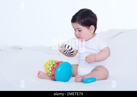 Kleines Mädchen (40 Wochen), das mit dem Ringspielzeug spielt Stockfoto