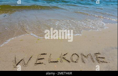 Handschreiber-Inschrift Welkome-Wort über tropischen Sandstrand, Reise-Konzeptkarte für Urlaub. Stockfoto