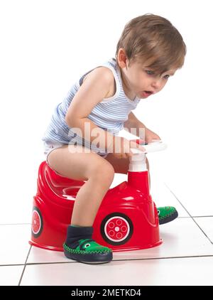 Junge sitzt auf einem Töpfchen wie ein Auto mit Lenkrad, 20 Monate geformt Stockfoto