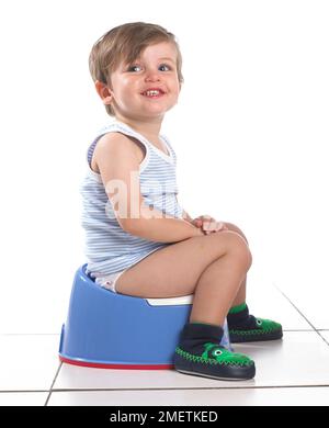 Junge sitzt auf einem blauen Töpfchen, 20 Monate Stockfoto